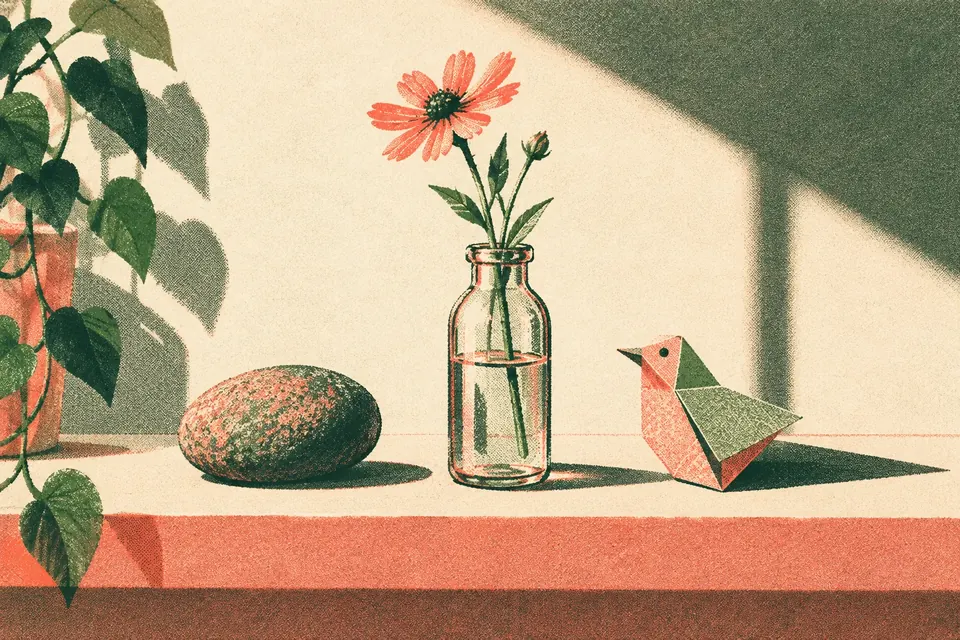 Drei kleine Dinge in einer Reihe auf einem Regal: ein glatter Flusskiesel, eine Wildblume in einer Glasflasche und ein Papiervogel