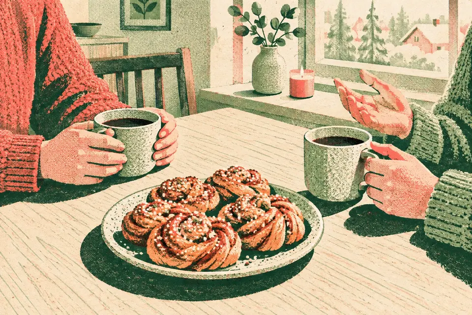 Zwei Tassen Kaffee und Zimtschnecken auf einem hellen Holztisch am Fenster, zwei Menschen in Pullovern unterhalten sich