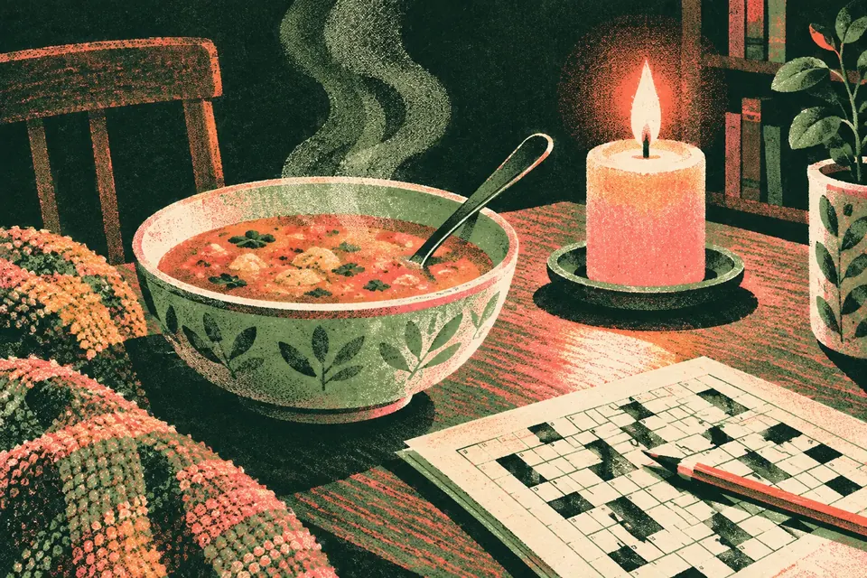 Nahaufnahme: eine dampfende Schüssel Suppe im Kerzenschein, daneben ein angefangenes Kreuzworträtsel